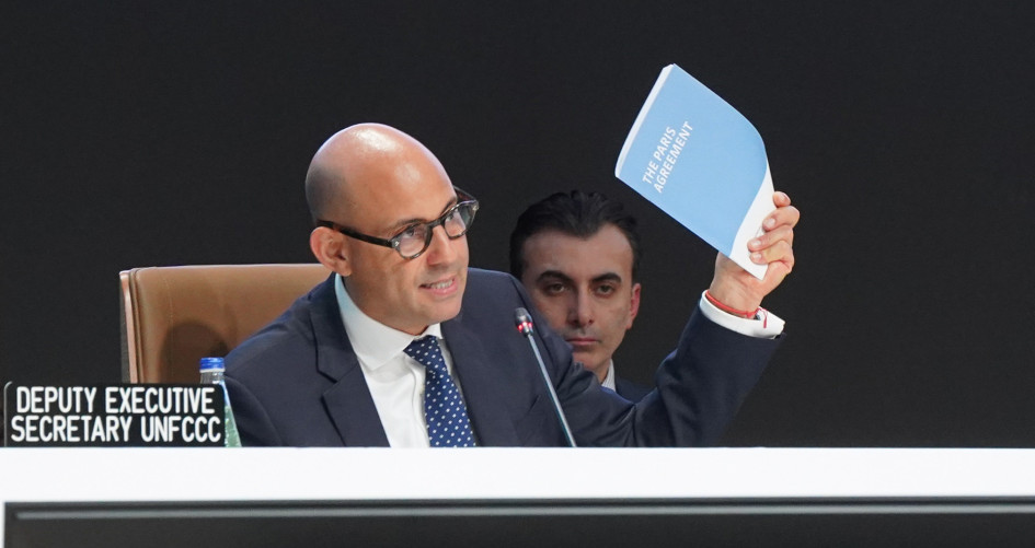 UN Climate Change Executive Secretary Simon Stiell holds up the Paris Agreement at the closing of COP29.