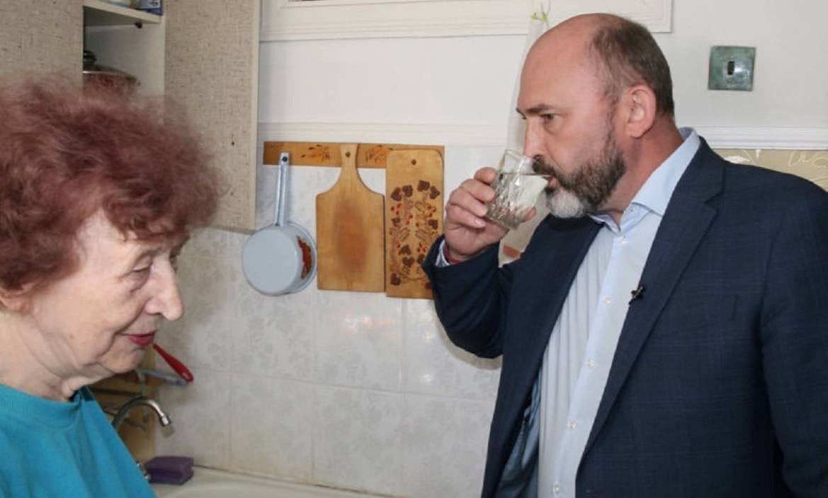 Антон Велиховский дегустирует воду у пенсионерки в подмосковном Дзержинске после подключения к новому водоводу