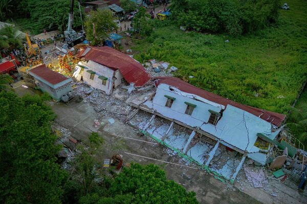 На этом снимке спасатели ищут выживших под завалами разрушенного жилого здания после землетрясения на Филиппинах - Sputnik Абхазия