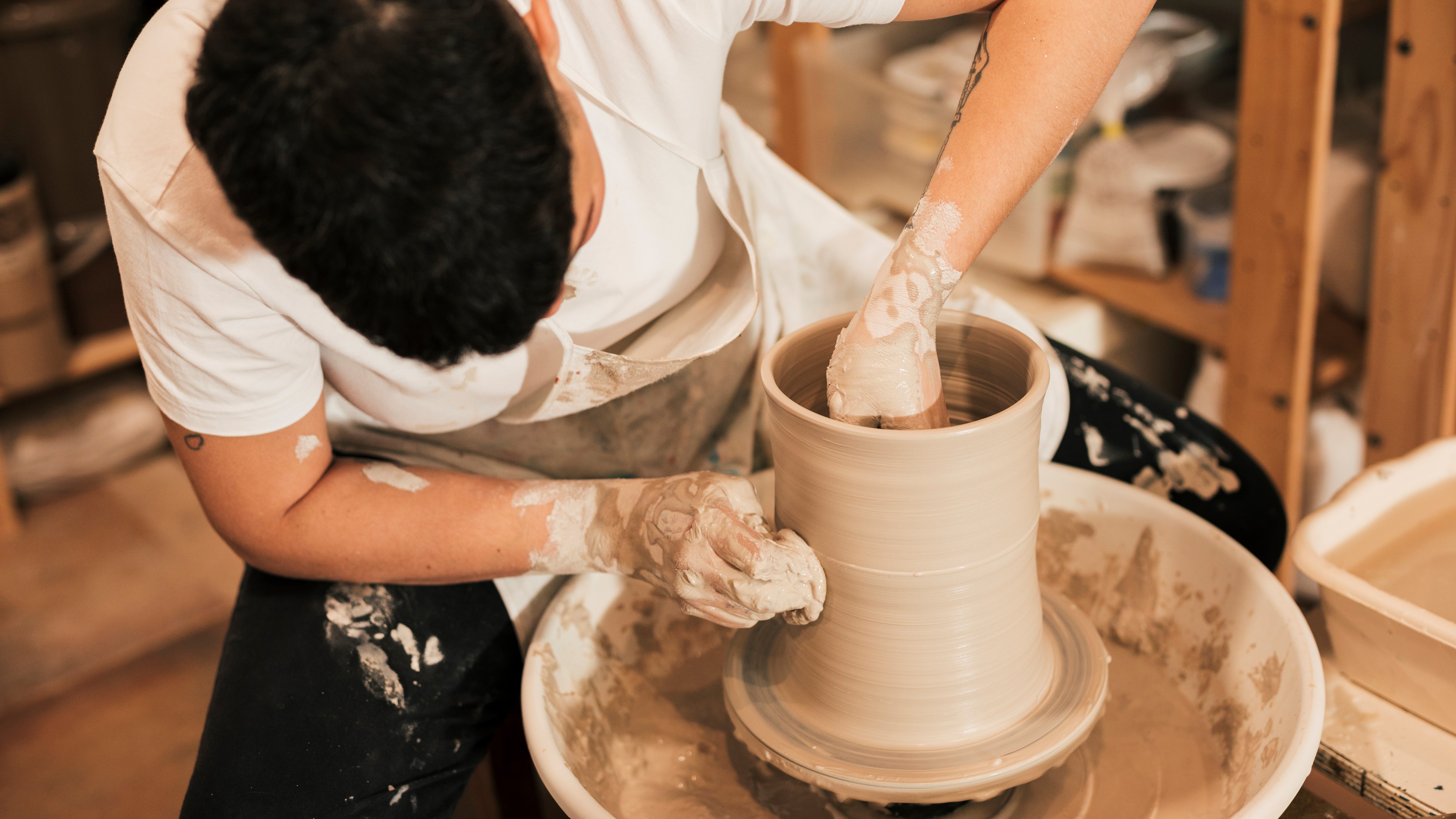 женщина гончар которая спасет мир. женщина в гончарной мастерской. девушка в фартуке лепит из глины. женщина ремесленница. девушка работает с глиной.