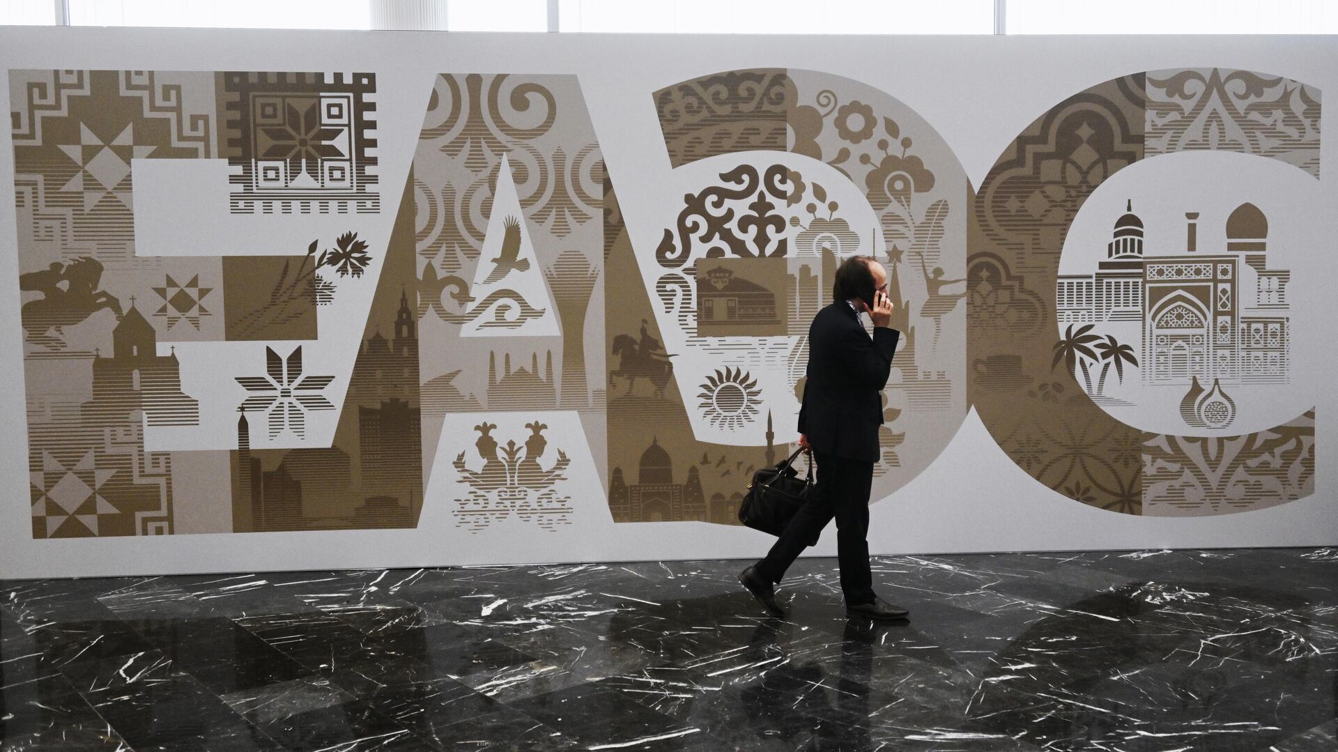 Участники проходят рядом со стендом с символикой Евразийского экономического форума - Sputnik Азербайджан, 1920, 25.03.2025