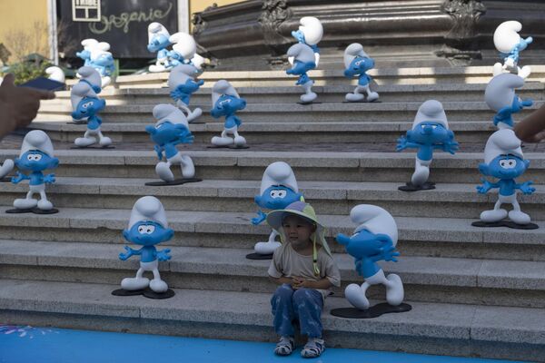 Ребенок стоит рядом с персонажами, рекламирующими новый фильм о смурфиках в Пекине - Sputnik Грузия