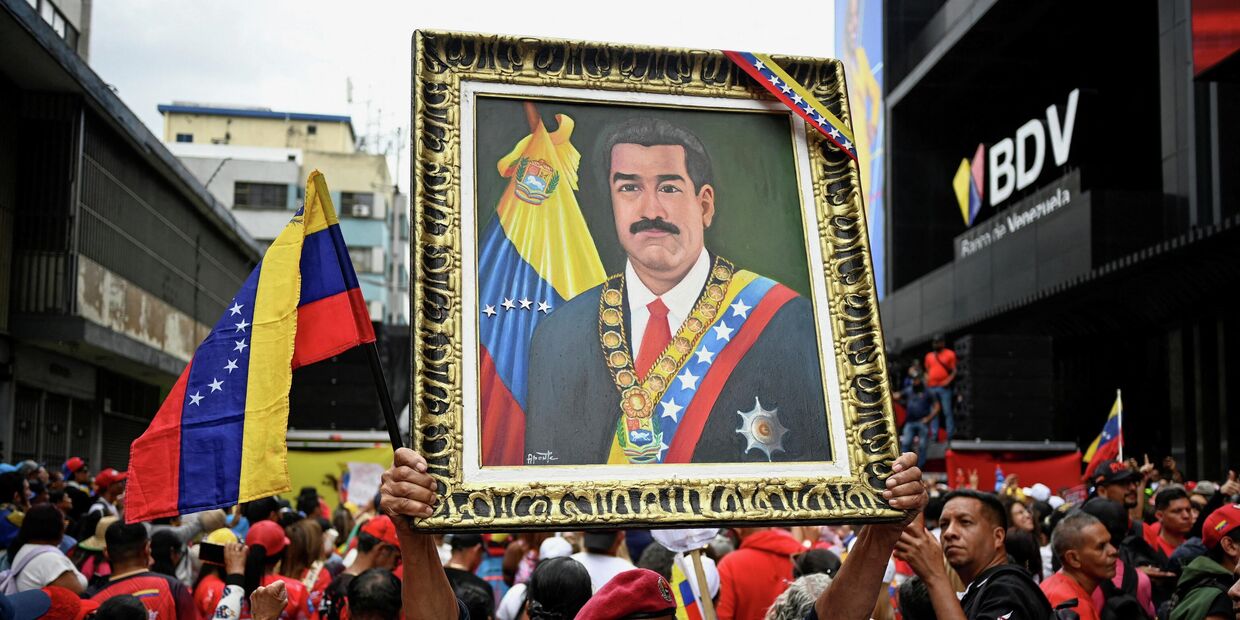 Демонстрант держит портрет президента Николаса Мадуро во время марша с требованием освободить Мадуро и его жену Силию Флорес, захваченных американскими войсками
