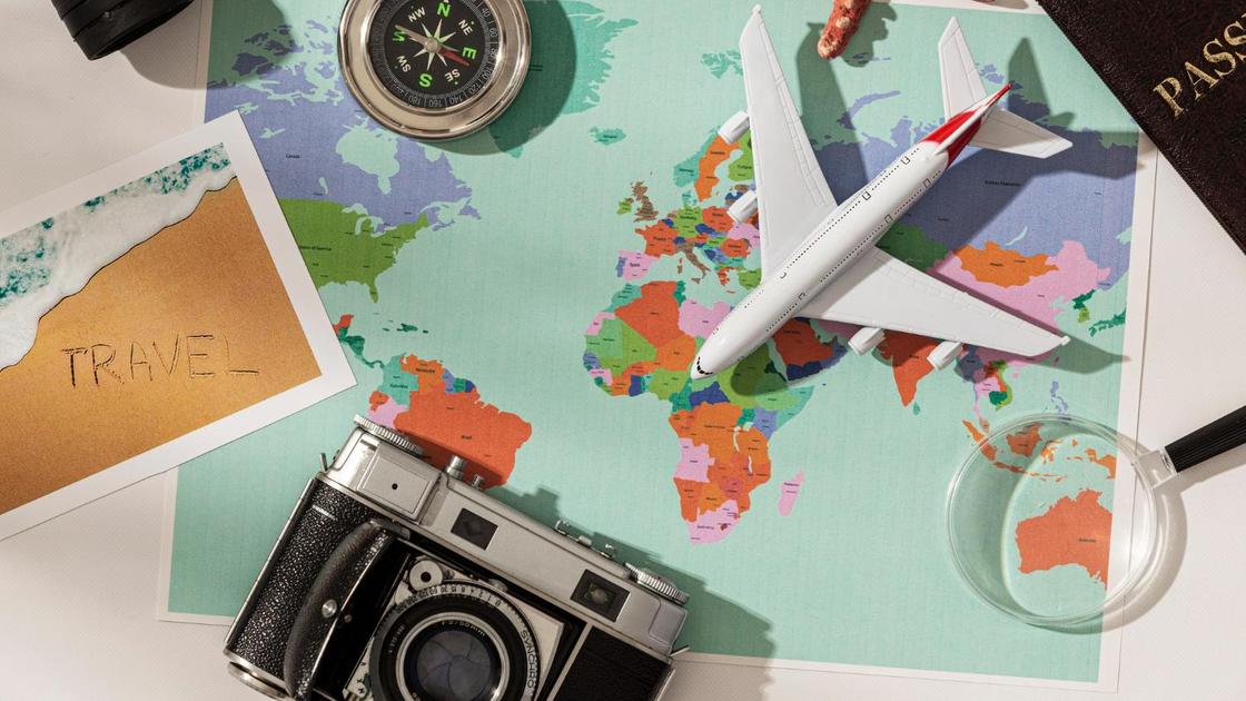 Карта, компас, фотоаппарат и миниатюрная модель самолета лежат на карте