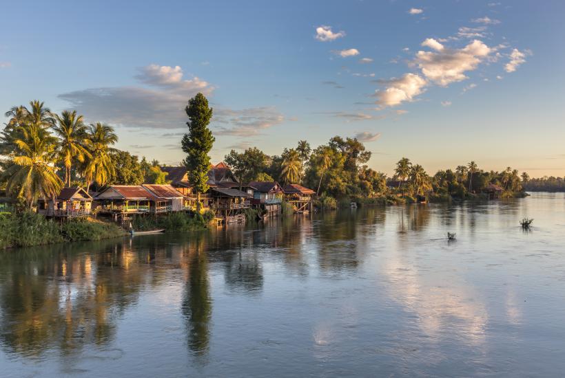 Mekong bank with stilt dwellings and clouds at golden hour in Don Det Laos