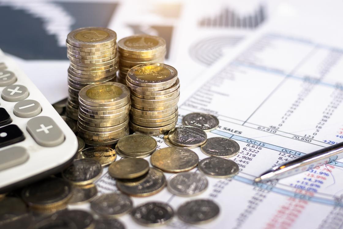 Монеты, калькулятор и ручка лежат на финансовом отчете