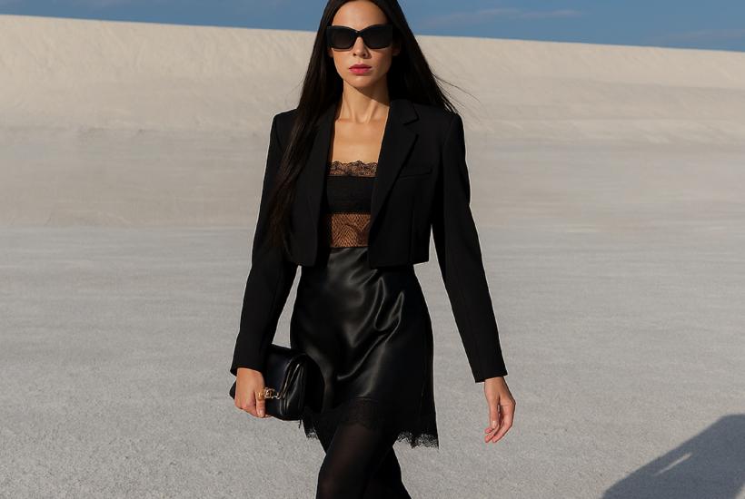 Женщина в чёрном жакете и платье на фоне песчаного пейзажа