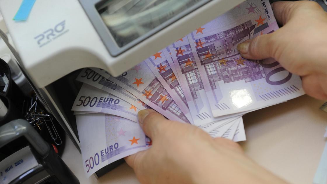 Кассир проверяет купюры евро на подлинность