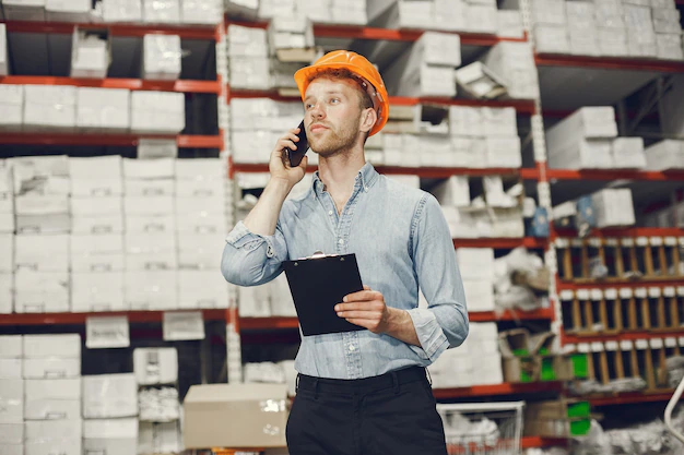 Industrial worker indoors in factory. businessman with orange hard hat. man in a blue shirt.