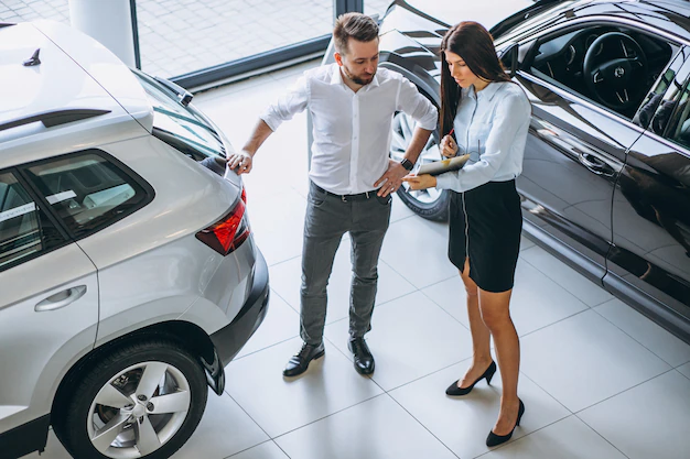 Salesman and woman looking for a car in a car showroom