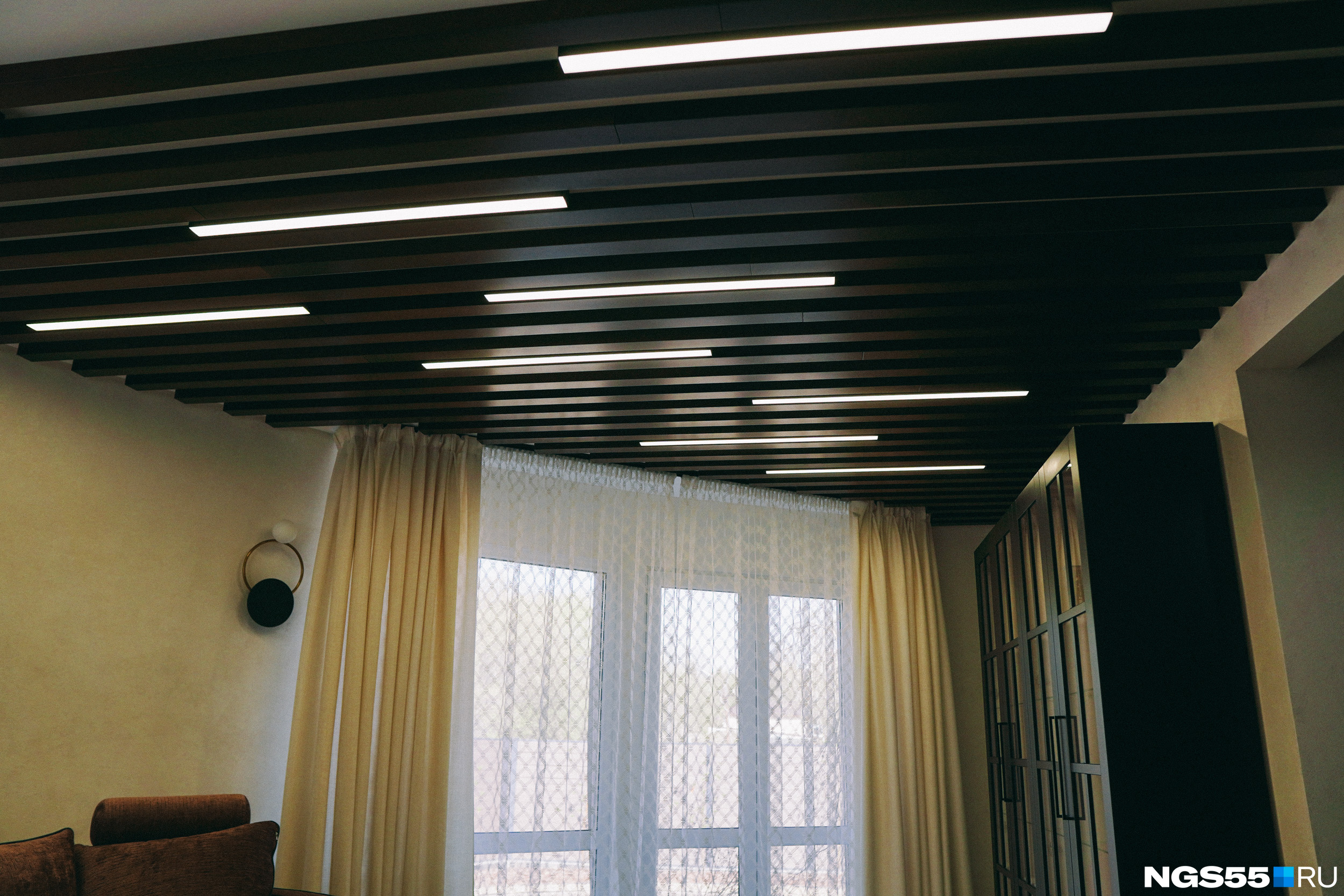 Потолок гостиной оформлен рейками со встроенными лампами