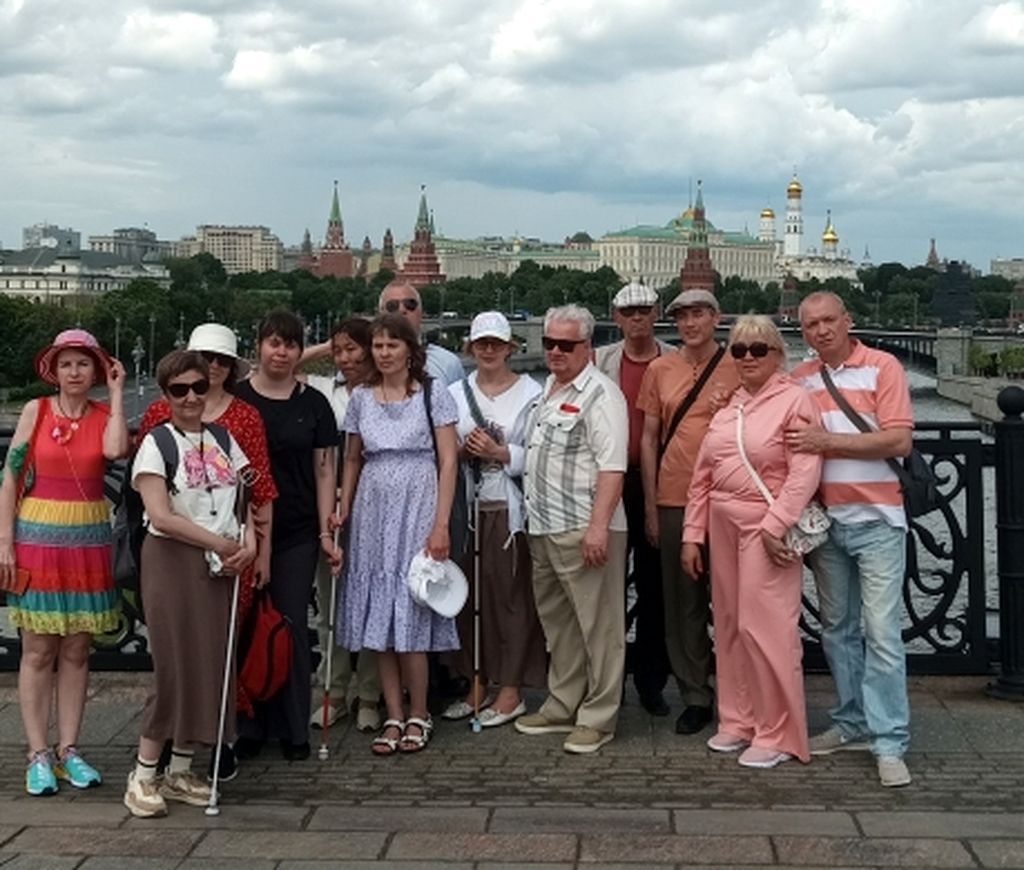 Групповое фото на фоне Московского Кремля. Трое участников с белой тростью, некоторые в чёрных очках.