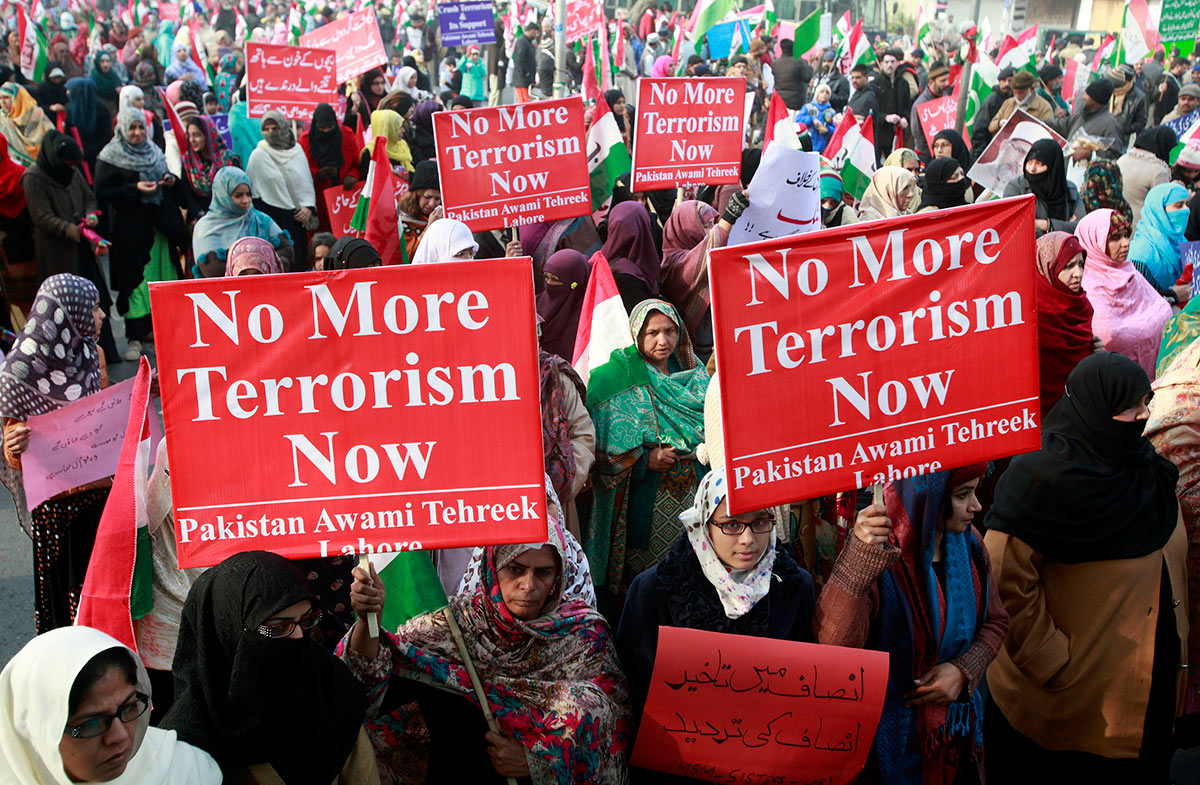 Люди держат плакаты с осуждением нападения боевиков Талибана на школу в Пешаваре