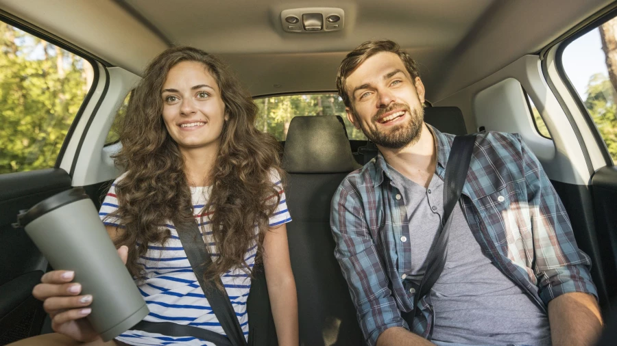 Мужчина и женщина едут на заднем сидении в автомобиле.