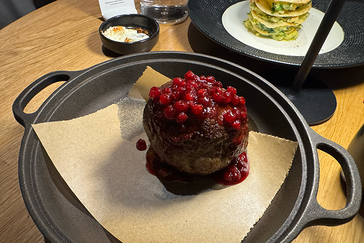 Котлета из конины с брусничным соусом и татарский мильфей с картофелем и белыми грибами (на заднем плане)