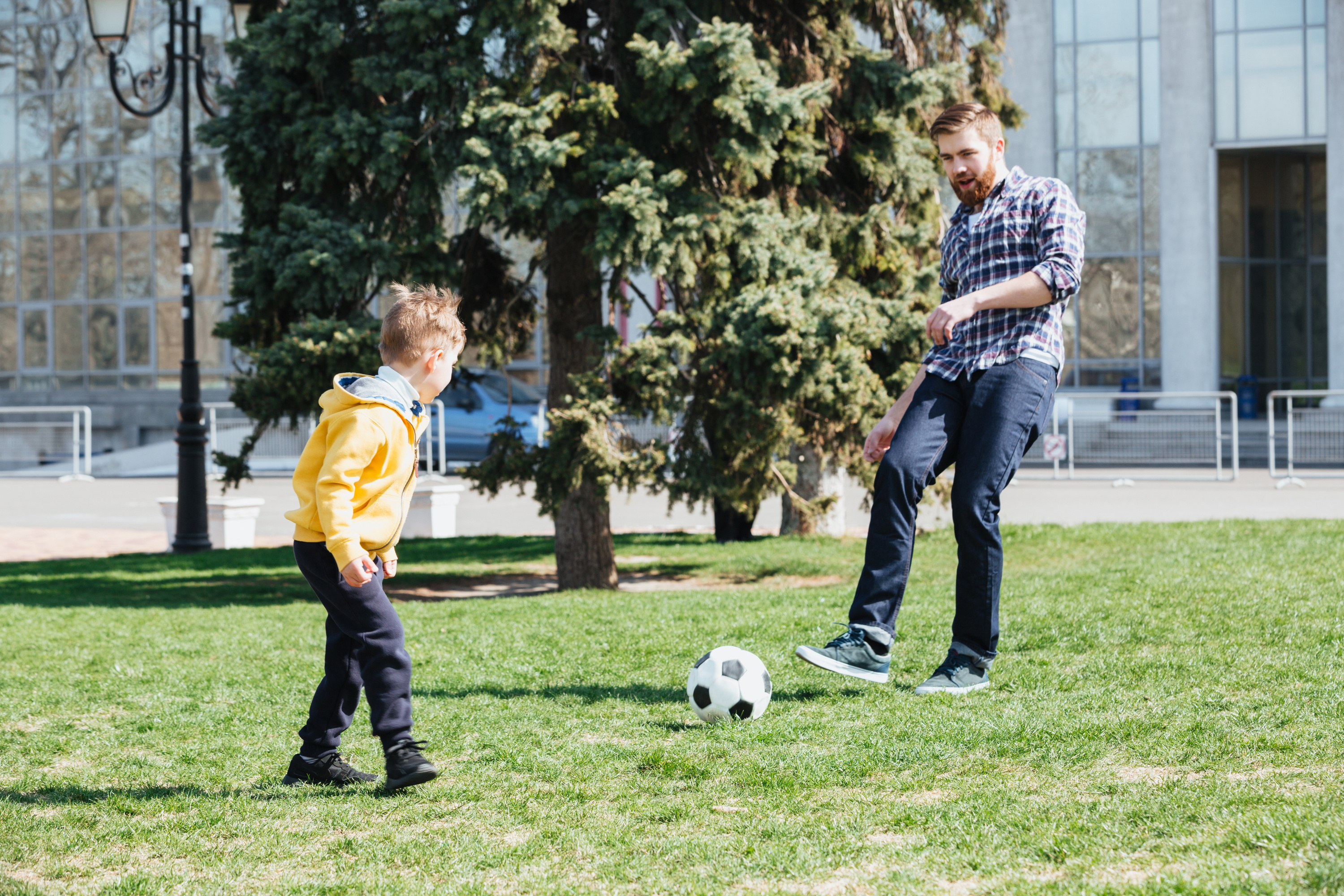 Футбол с папой. Папа играет в футбол. Отец и сын играют в футбол. Young father and his son playing Football in a Park. Сын играет в футбол
