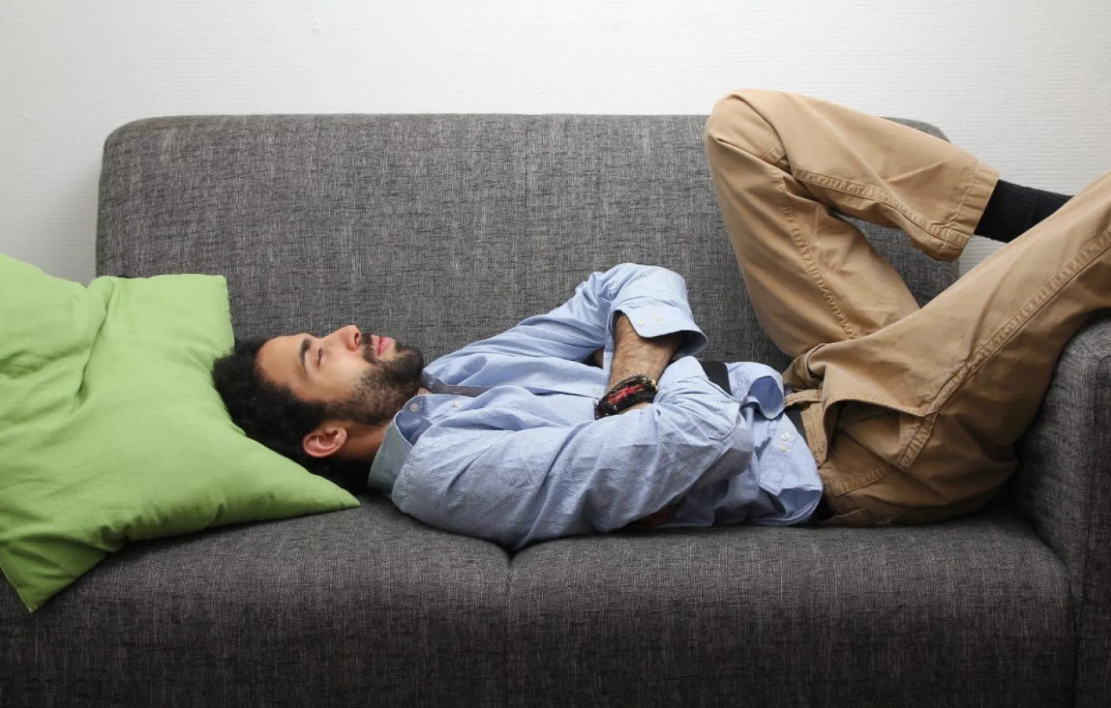 Неприятный лежать. Девушка устала. Опасные позы для сна. Мужчина лежит на диване. Женщина лежит на диване болит живот.