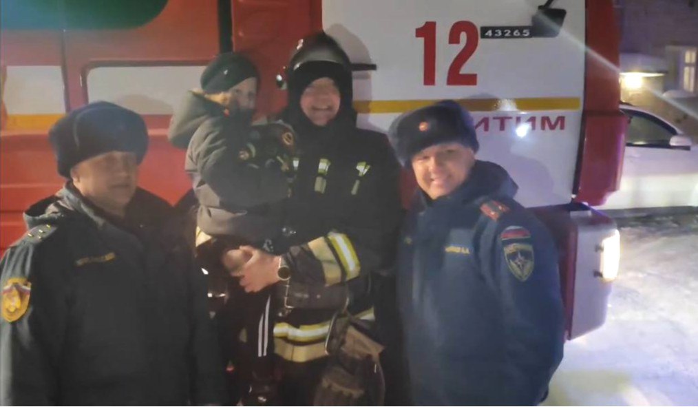 Сотрудники МЧС со спасенным ребенком