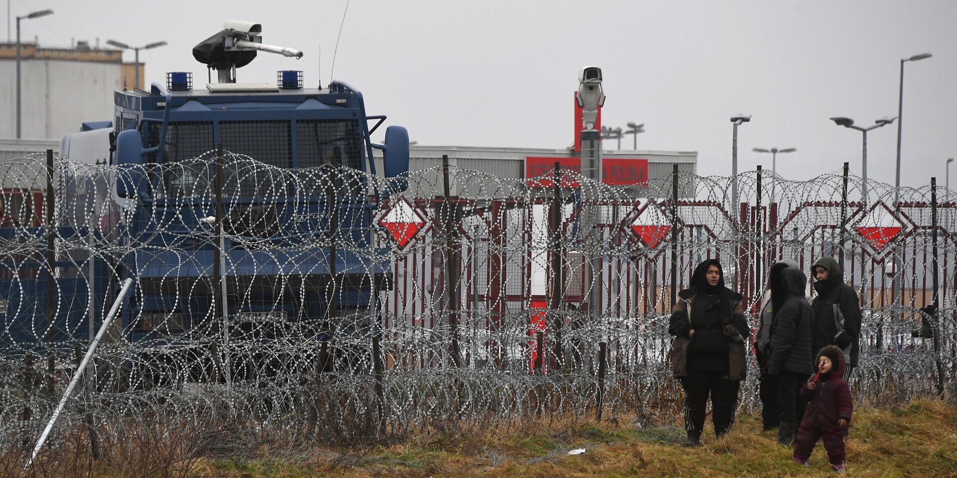 Люди из лагеря нелегальных мигрантов и польская полицейская спецтехника у лагеря нелегальных мигрантов на белорусско-польской границе. 8 ноября больше тысячи находящихся в Белоруссии беженцев из стран Ближнего Востока и Северной Африки выдвинулись в сторону польской границы. Власти Польши расценили это как крупнейшую попытку массового силового проникновения и усилили охрану границы.ейшую попытку массового силового проникновения и усилили охрану границы. - ИноСМИ, 1920, 31.12.2025