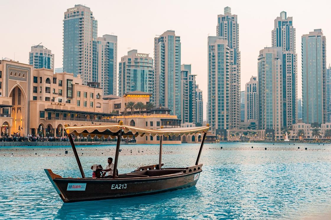 Деревянная лодка, проплывающая по воде на фоне небоскребов Дубая