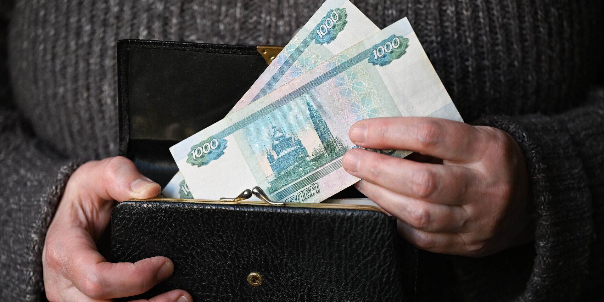 Женщина держит кошелек с тысячными рублевыми купюрами. - ИноСМИ, 1920, 26.06.2025