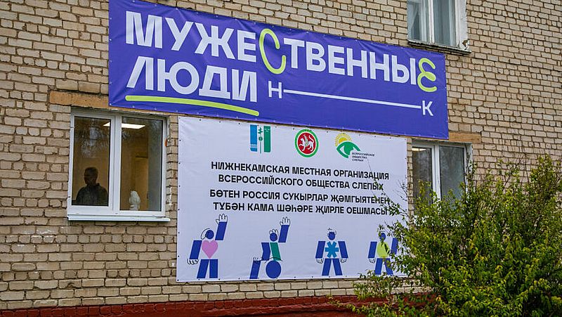 Стена нового здания. на стене надпись: Мужественные люди и название организации